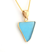 Necklace with a blue triangular pendant and gold chain on a white background