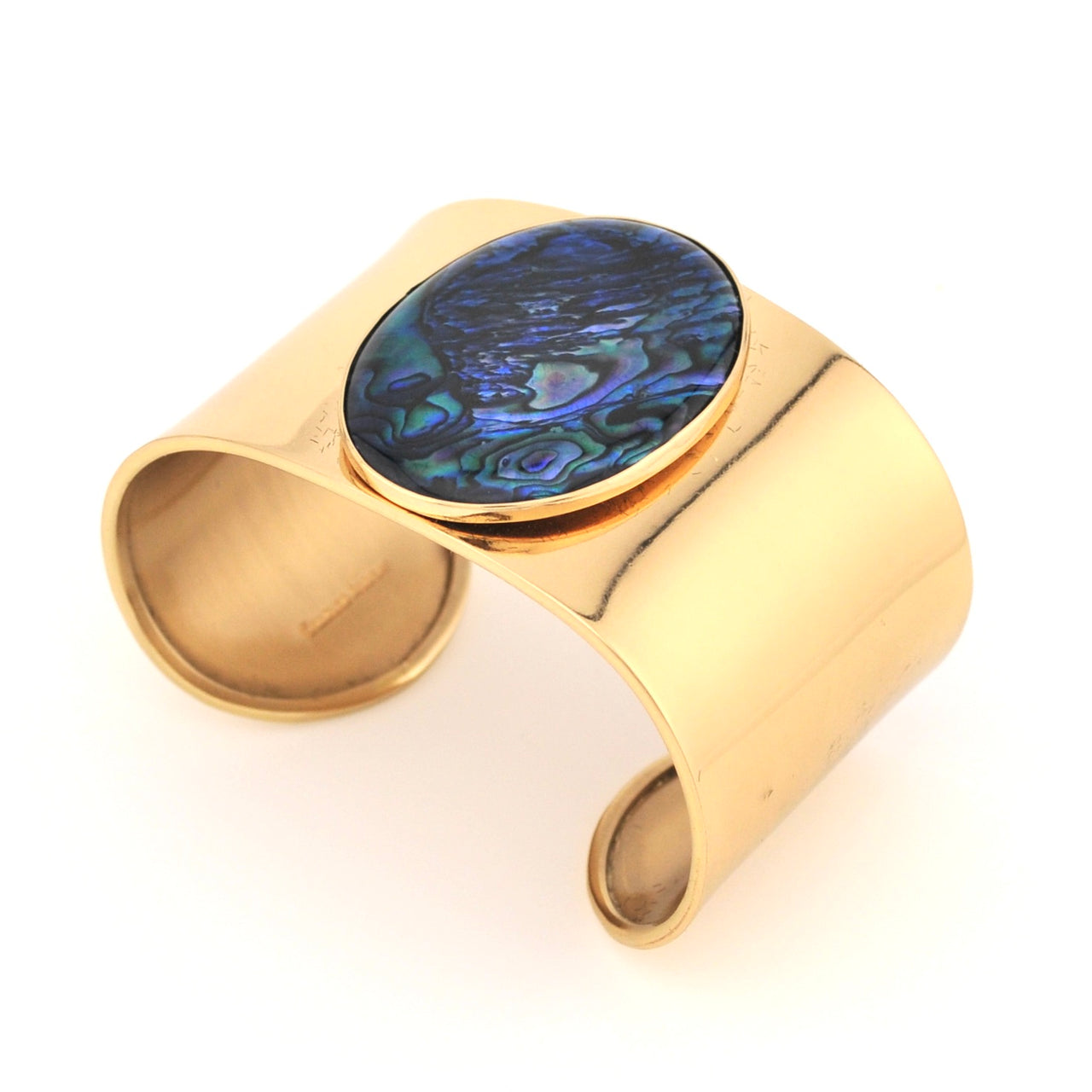 Gold cuff bracelet with a colorful stone on a white background