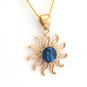 Gold sun-shaped pendant with a blue center on a white background