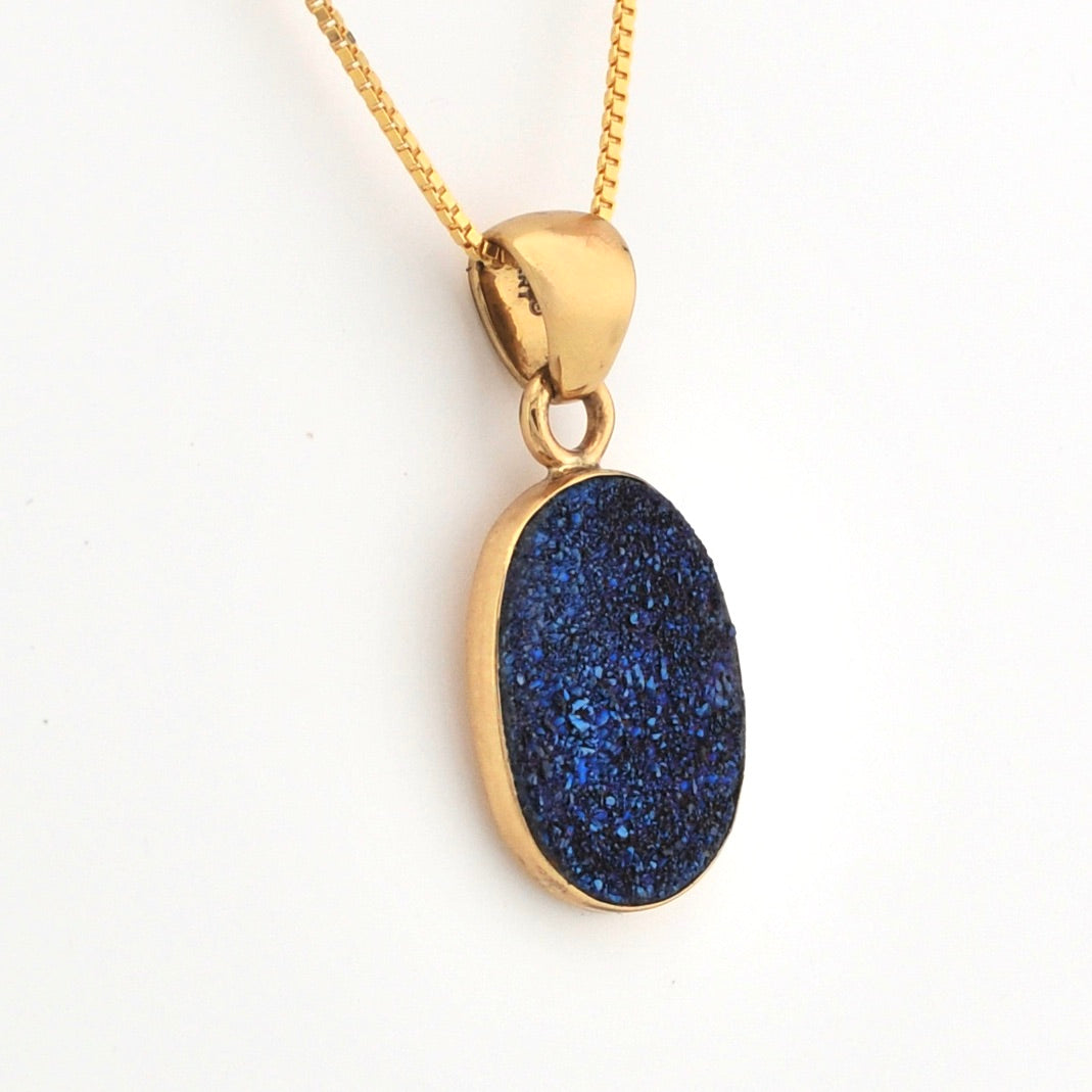 Gold necklace with a blue pendant on a white background