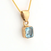 Gold pendant with a blue gemstone on a white background