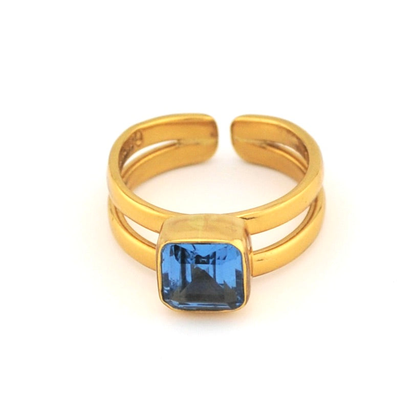 Gold ring with a blue gemstone on a white background