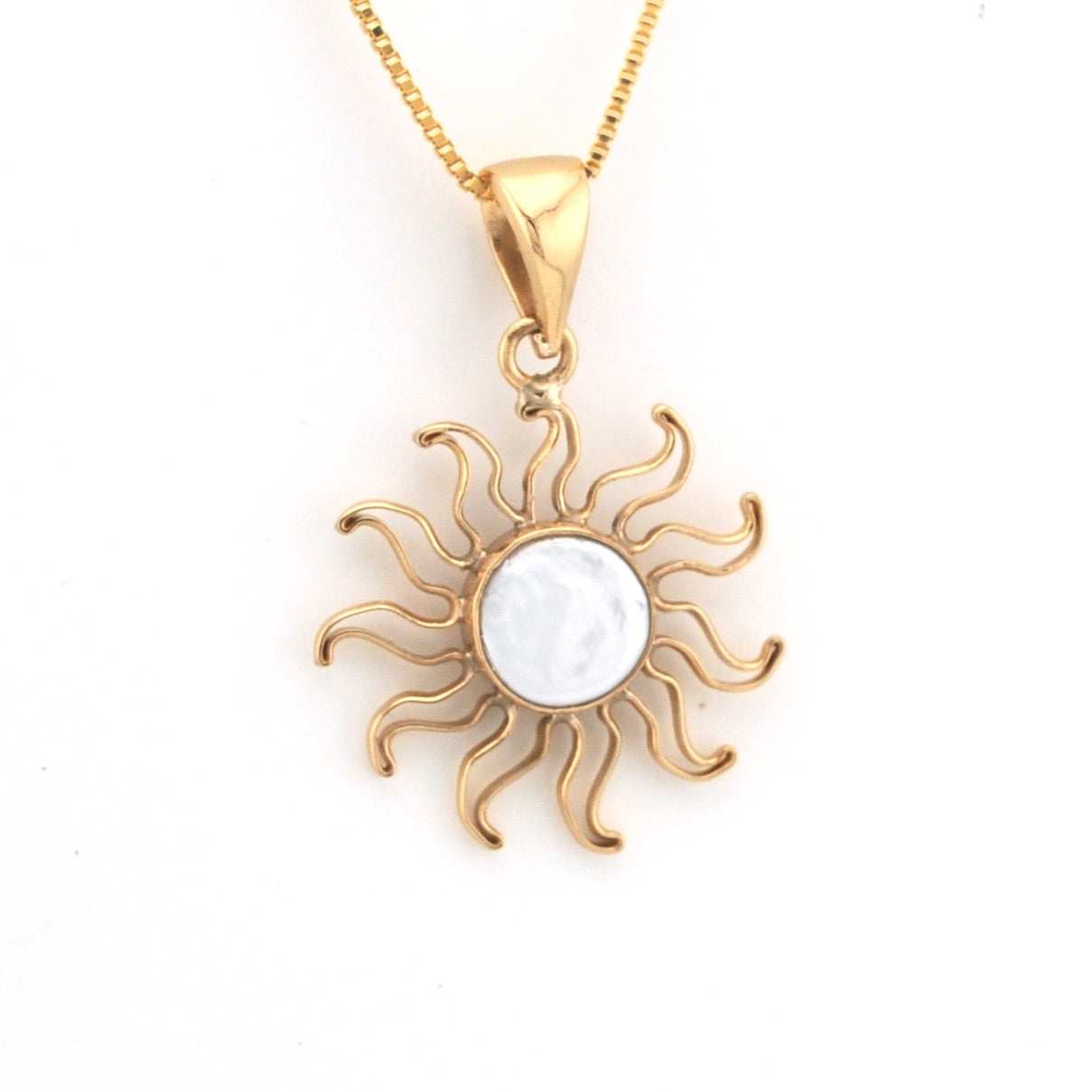 Gold sun-shaped pendant with a white center on a gold chain against a white background