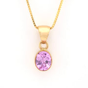 Gold necklace with a pink gemstone pendant on a white background