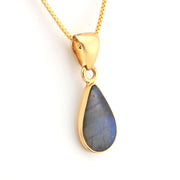 Gold pendant with a blue stone on a white background