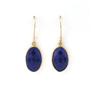Gold earrings with blue gemstones on a white background
