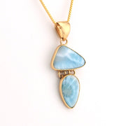Gold necklace with a pendant featuring two blue stones on a white background