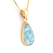 Gold pendant with a blue teardrop-shaped stone on a white background