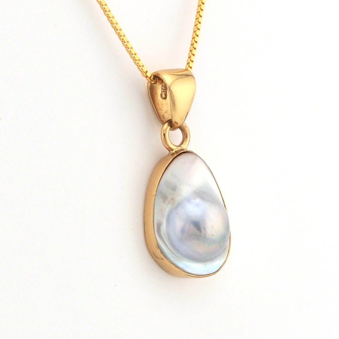 Gold pendant with a teardrop-shaped gemstone on a white background