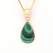 Gold necklace with a green teardrop pendant on a white background