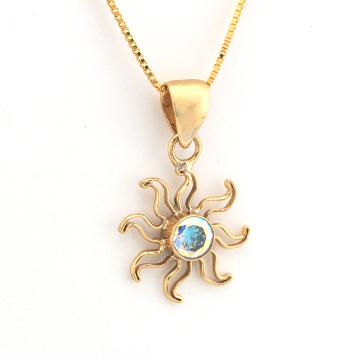 Gold sun-shaped pendant with a central gemstone on a white background