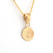 Gold necklace with a round pendant on a white background