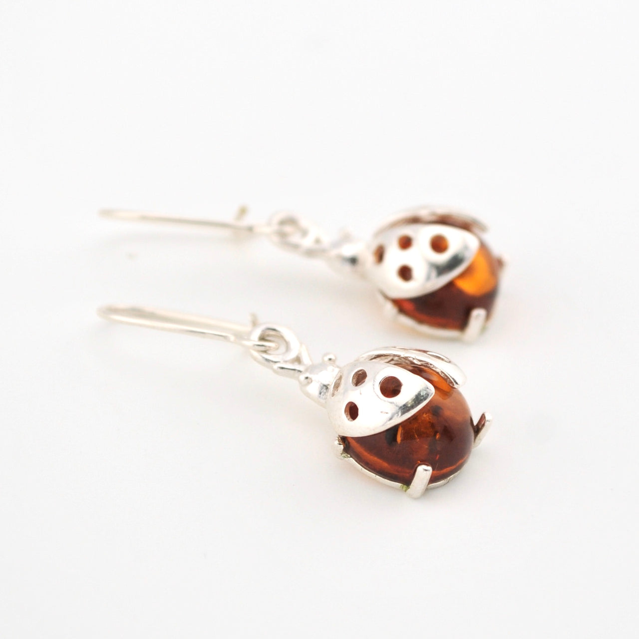 Ladybug amber earrings with silver hooks on a white background