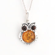 Silver owl pendant with amber center and brown stones on a white background