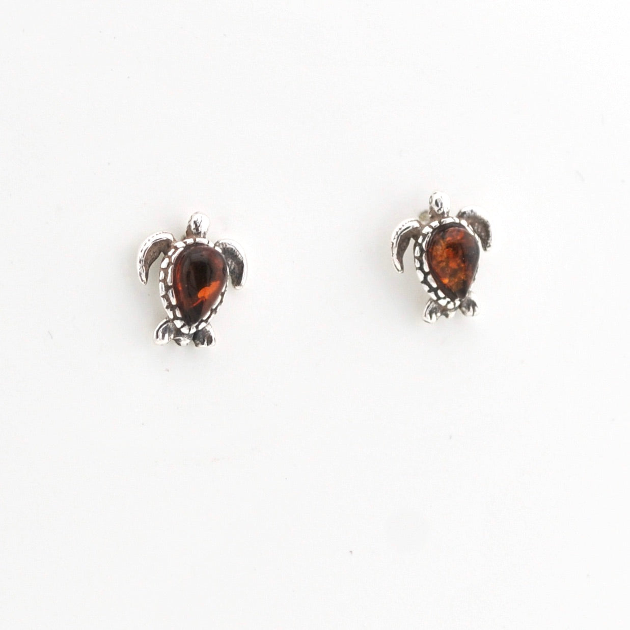 Pair of turtle-shaped earrings with amber stones on a white background