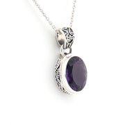 Silver pendant with a purple gemstone on a white background