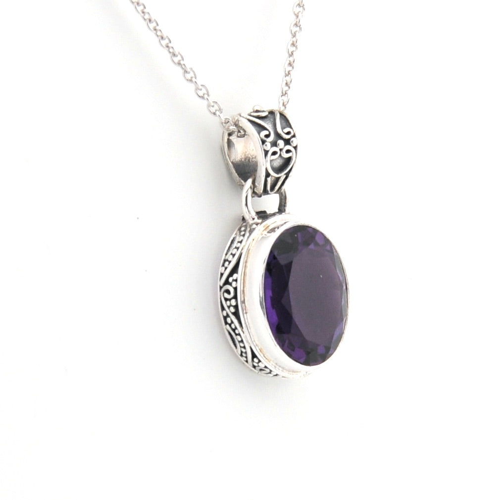 Silver pendant with a purple gemstone on a white background