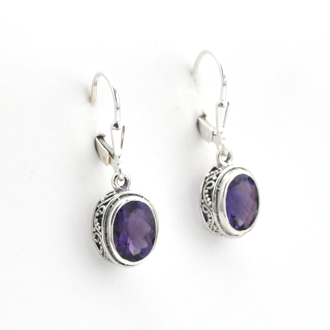 Silver earrings with purple gemstones on a white background