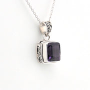 Silver pendant with a purple gemstone on a white background