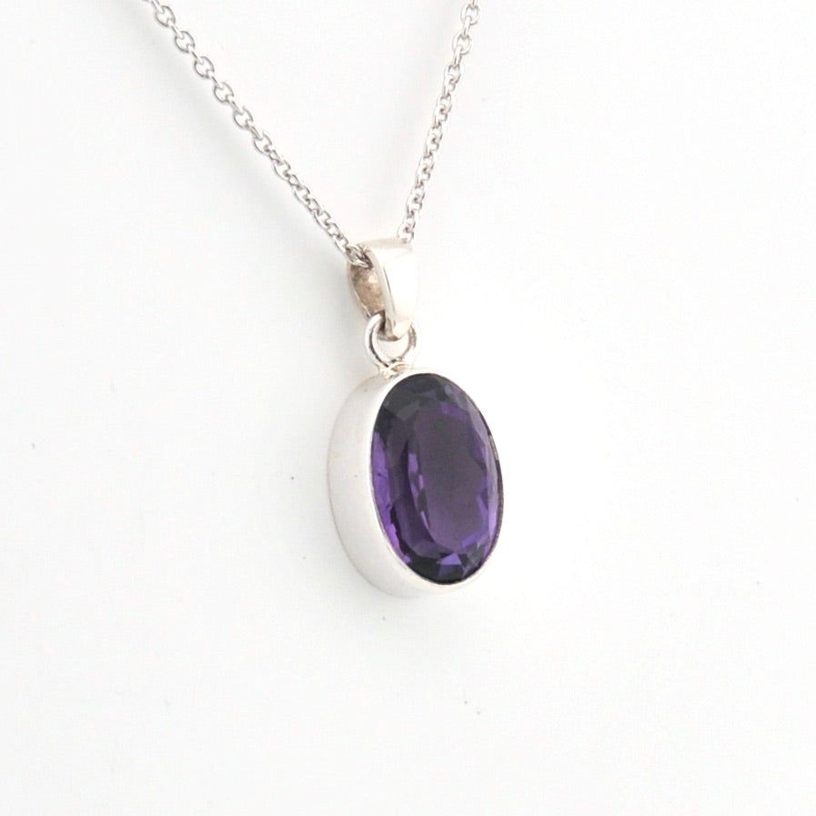 Silver necklace with a purple gemstone pendant on a white background