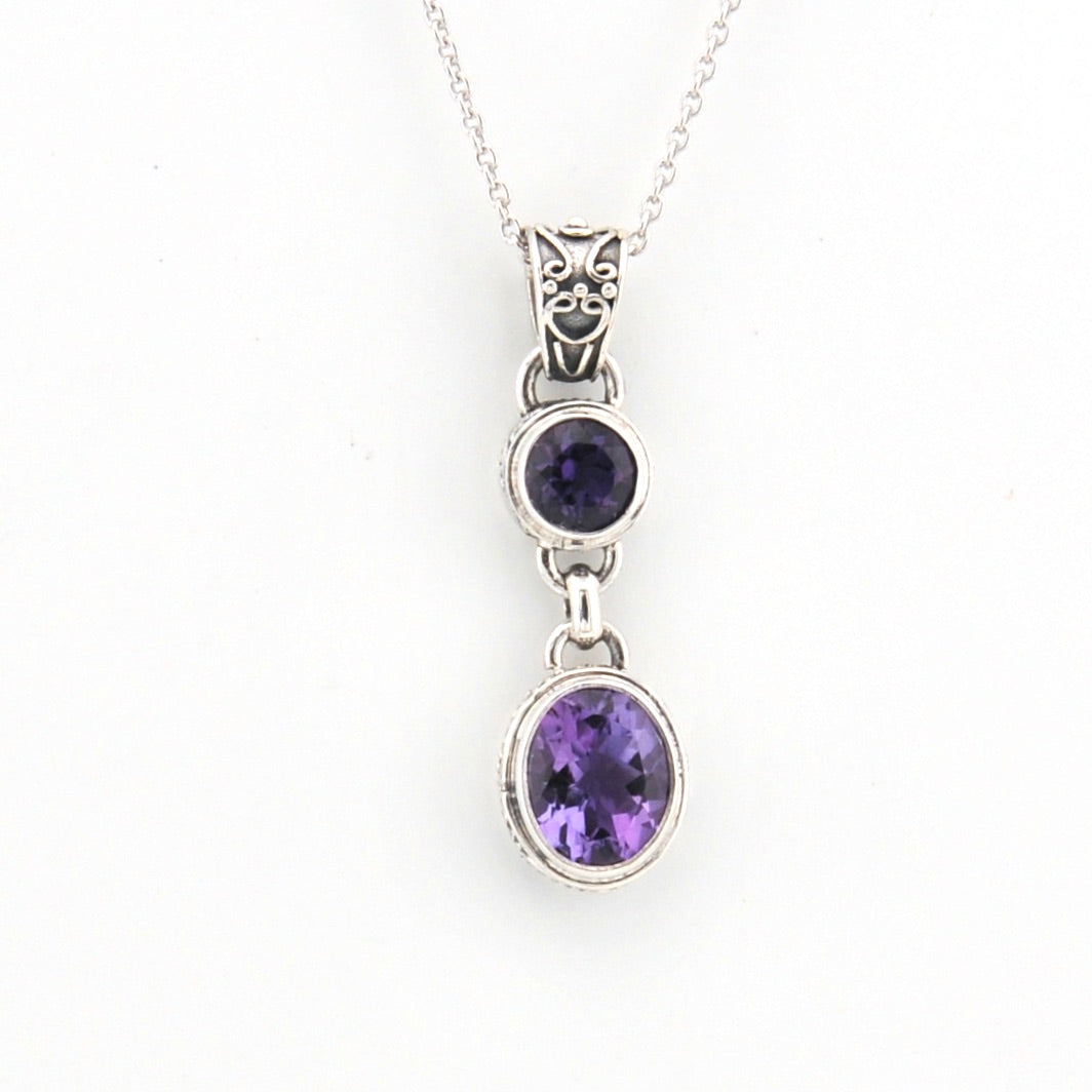 Silver necklace with two purple gemstones on a white background