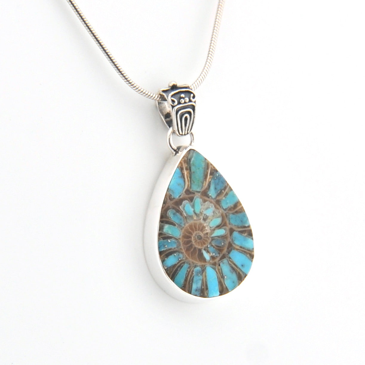 Teardrop-shaped pendant with blue and brown design on a white background