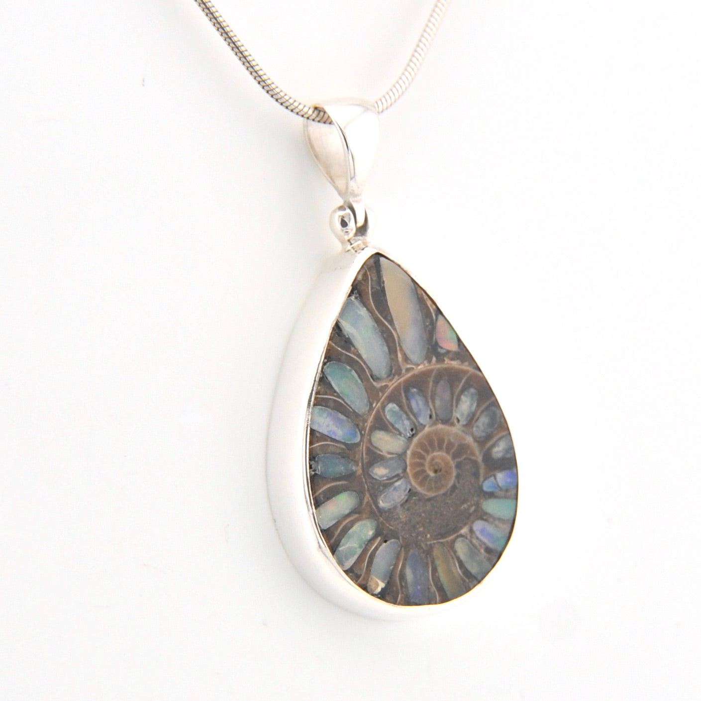 Teardrop-shaped pendant with fossil design on a white background
