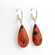 Teardrop-shaped amber earrings with silver hooks on a white background