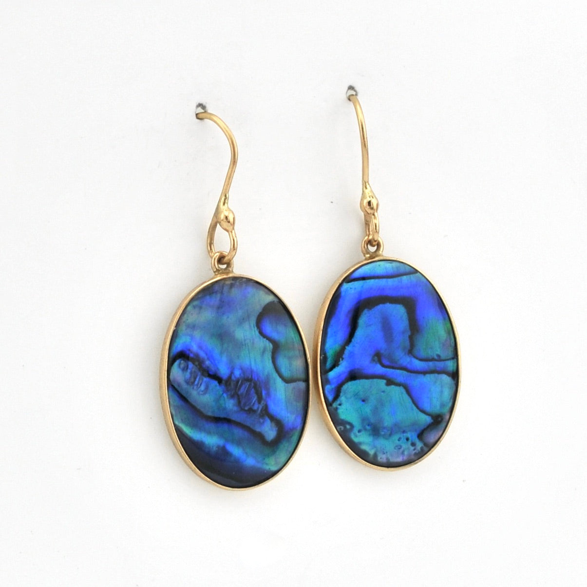 Gold earrings with blue paua shell drops on a white background