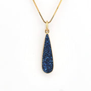 Gold necklace with a blue pendant on a white background