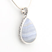 Teardrop-shaped pendant with blue and white marbled stone and silver frame on a white background