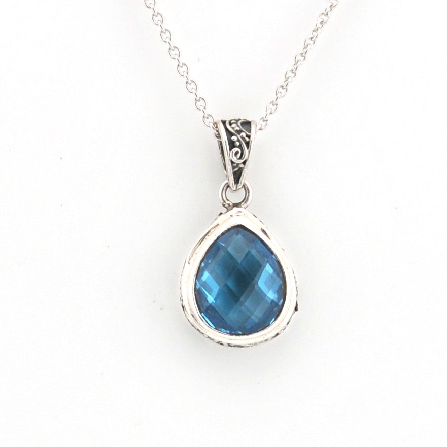 Silver necklace with a blue teardrop pendant on a white background