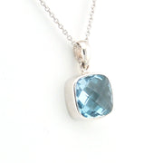 Silver pendant with a blue gemstone on a white background