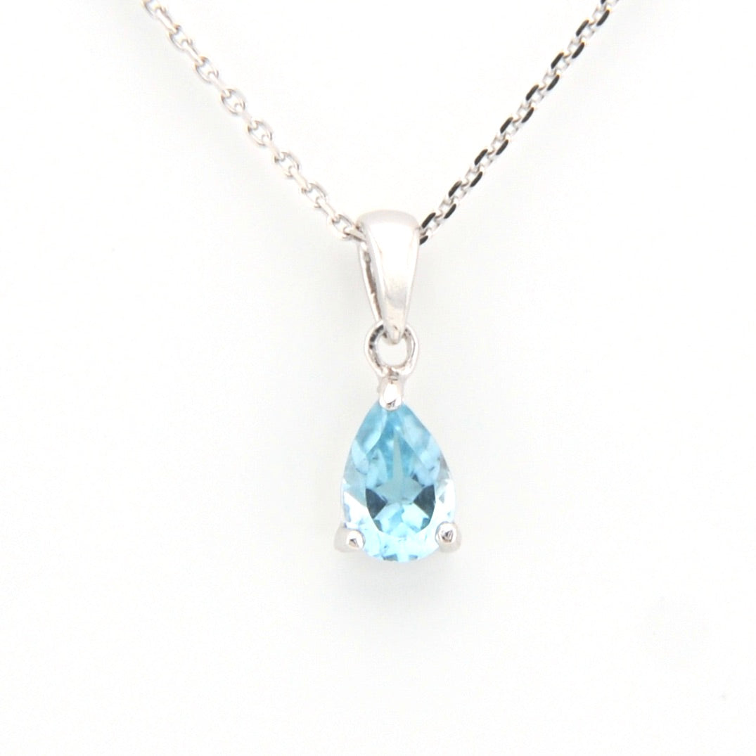 Teardrop-shaped blue gemstone pendant on a silver chain against a white background