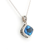 Silver pendant with a blue gemstone on a white background