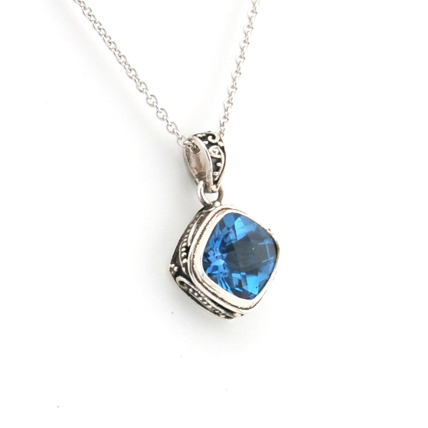 Silver pendant with a blue gemstone on a white background