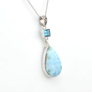 Teardrop-shaped larimar pendant with blue topaz on a white background
