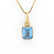 Gold necklace with a blue gemstone pendant on a white background