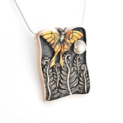Luna moth pendant on a white background