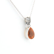 Teardrop-shaped pendant with golden gemstone on a silver chain against a white background