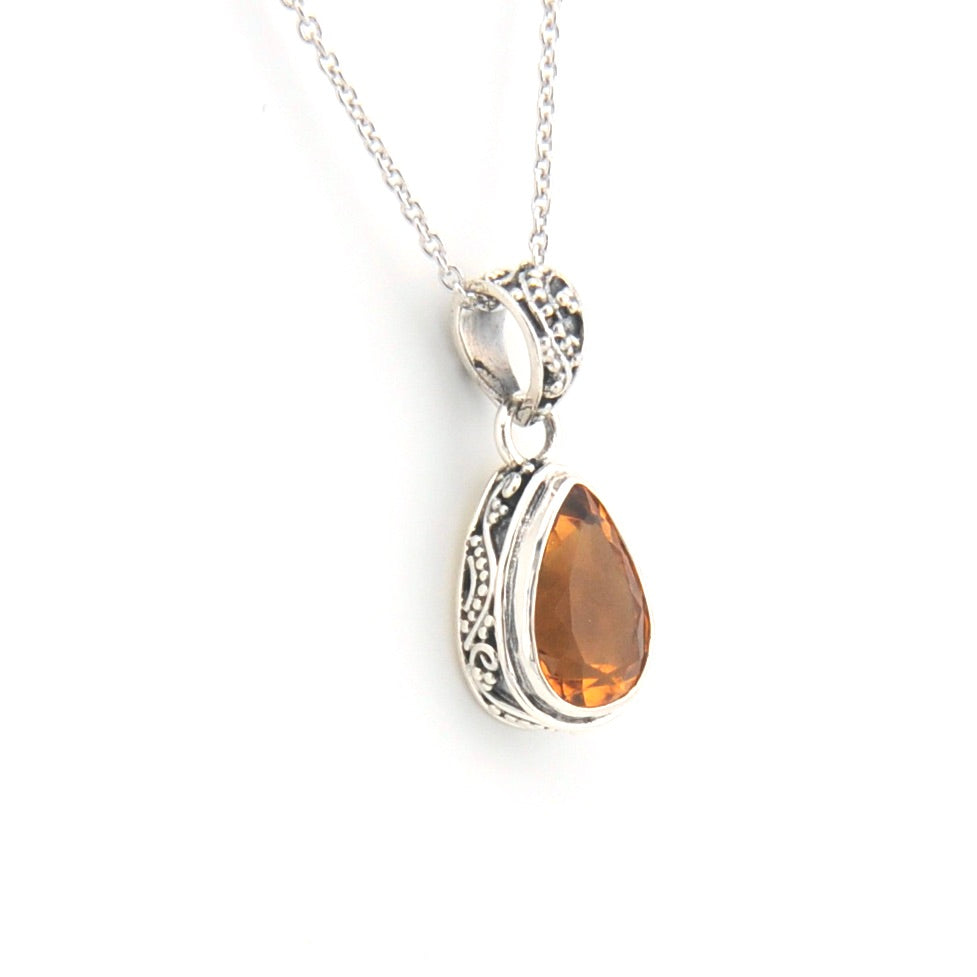 Silver pendant with a teardrop-shaped citrine stone on a white background
