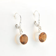 Pair of silver earrings with amber-colored stones on a white background