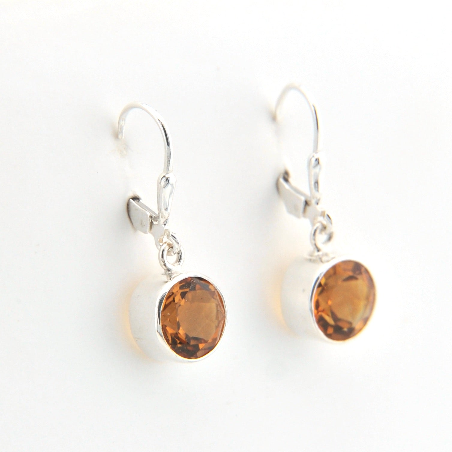 Pair of silver earrings with amber-colored stones on a white background