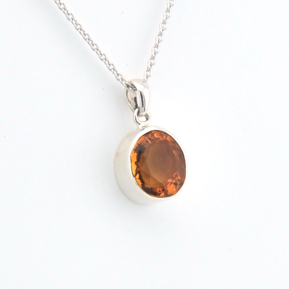 Silver necklace with a round citrine pendant on a white background