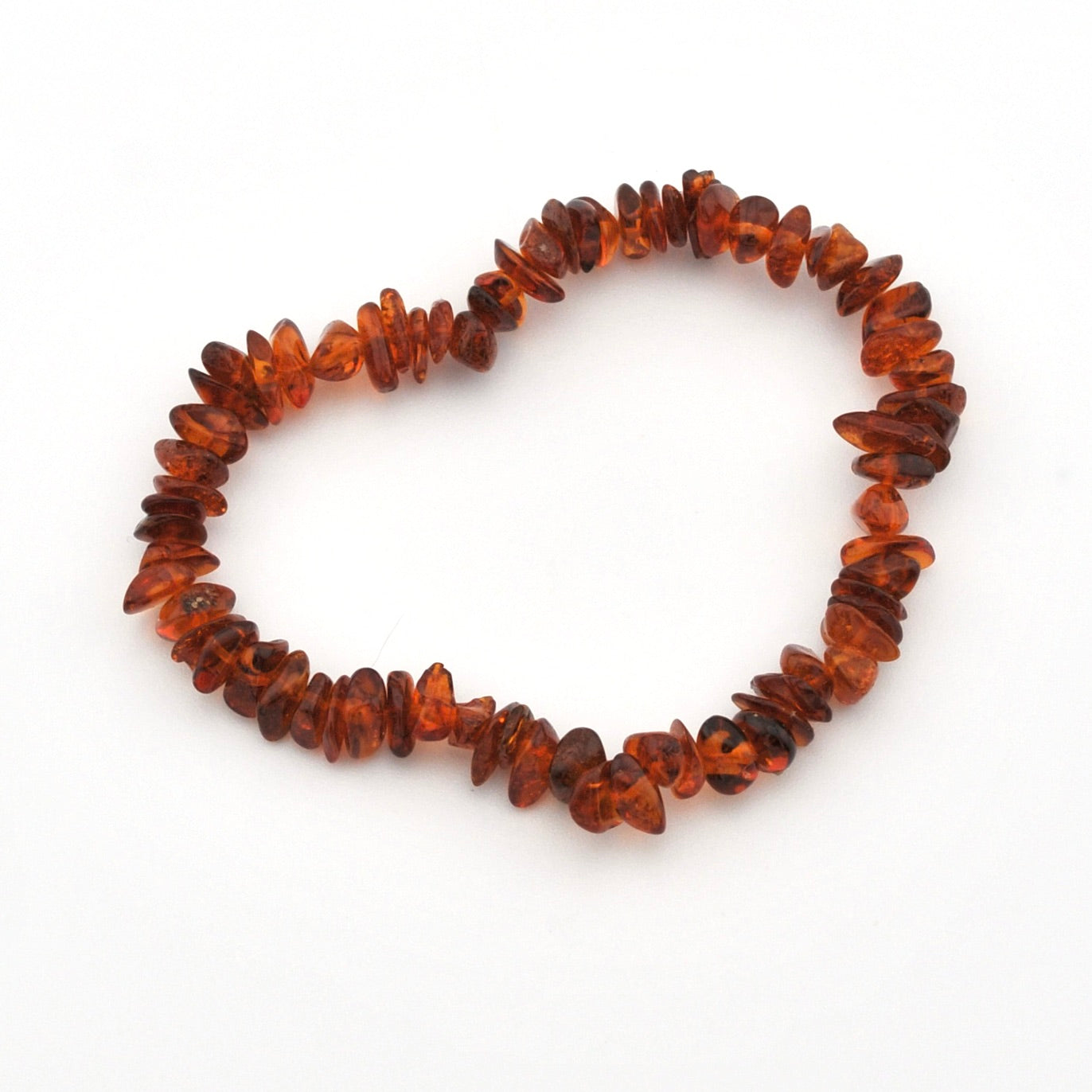 A handmade beaded bracelet made of polished, irregular amber chips in warm reddish-brown and orange tones, arranged in a circle on a plain white background.
