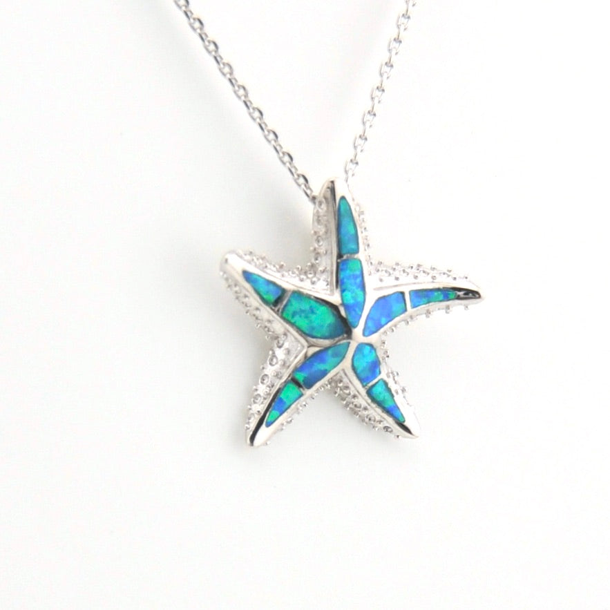 Star-shaped pendant with blue opal inlay on a white background