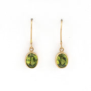 Gold earrings with green gemstones on a white background