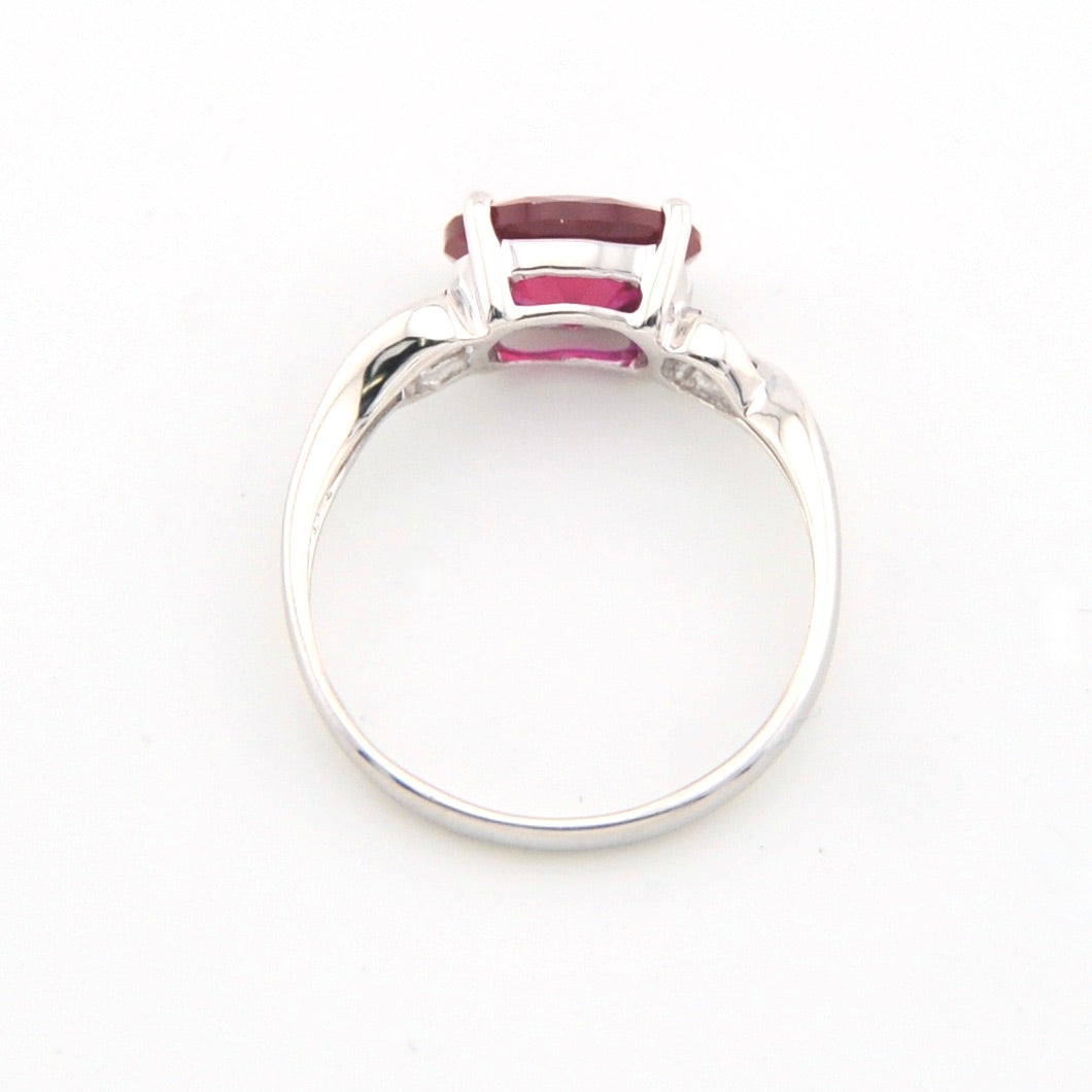 Silver ring with a red gemstone on a white background
