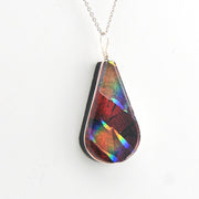 Teardrop-shaped pendant with multicolored iridescent surface on a white background