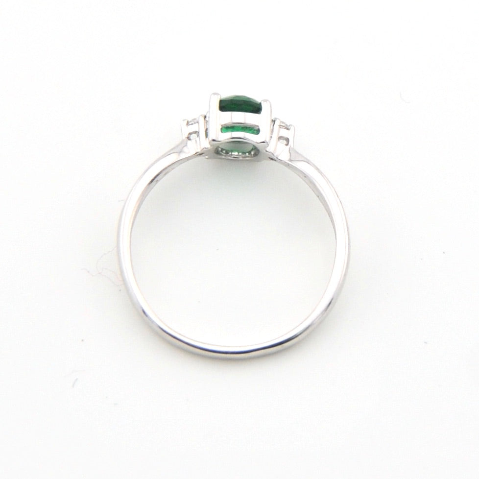 Silver ring with a green gemstone on a white background